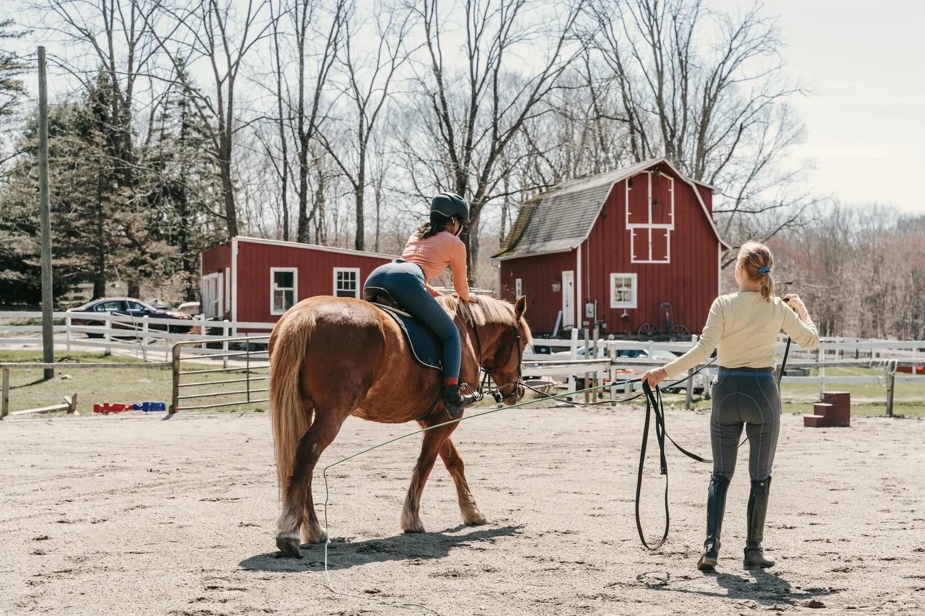 Beginnende ruiter op een paard aan de longe, met de instructeur in het midden van de rijbaan