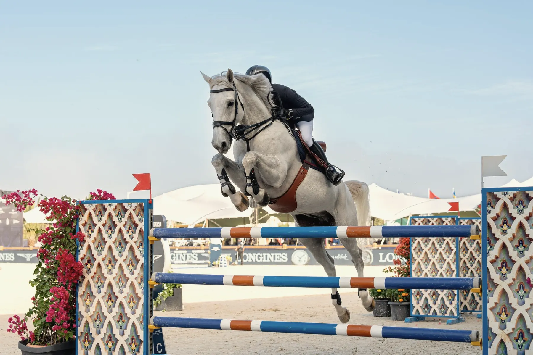 Ruiter en paard springen over een hindernis tijdens een springwedstrijd